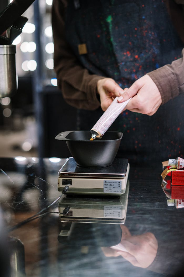 A stylist measures dye in a salon, showcasing the preparation process for hair coloring.