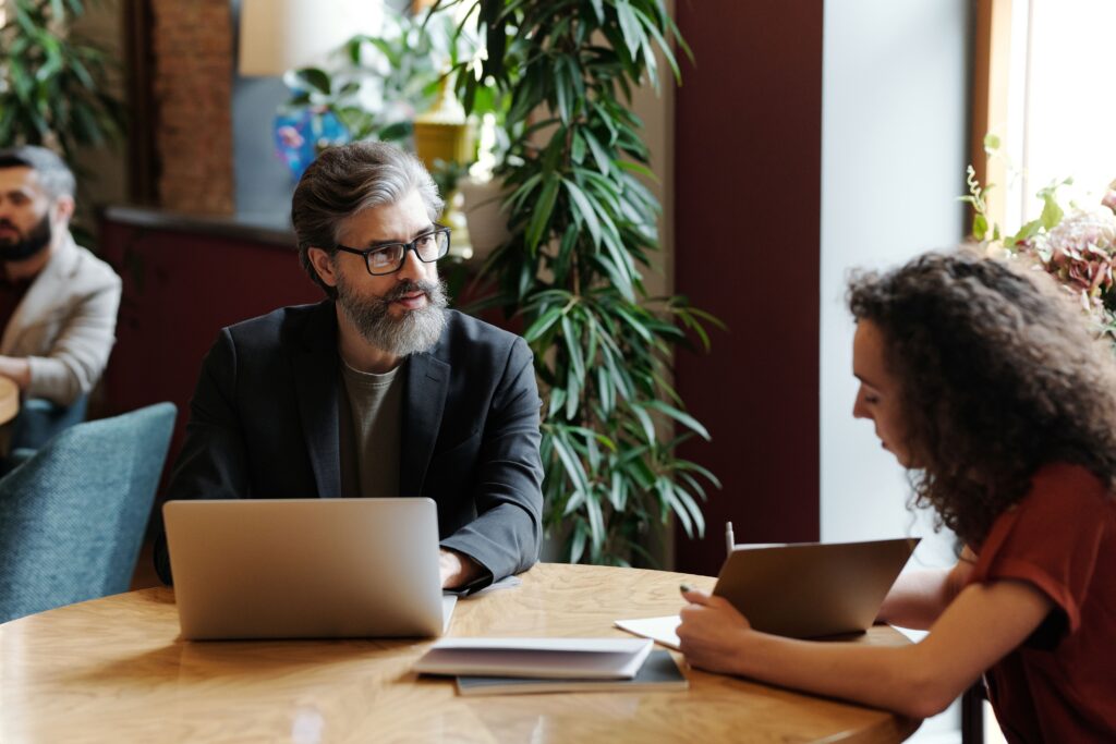 Professionals engaged in a business discussion at an indoor office setting, surrounded by greenery.